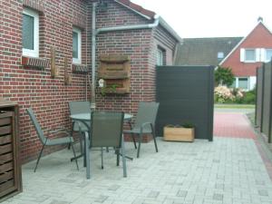 a patio with a table and chairs and a brick wall at NEU! Ferienwohnung Kruse EG in Norden