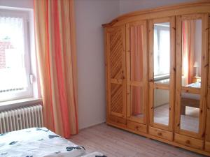 a bedroom with a large wooden cabinet next to a window at NEU! Ferienwohnung Kruse EG in Norden