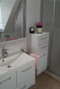 een witte badkamer met een wastafel en een klok bij NEU! Ferienwohnung Cottbus nähe Spreewald in Cottbus