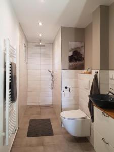 a white bathroom with a toilet and a sink at NEU! Modernes Ferienhaus Hohensayn in Lautzenbrücken