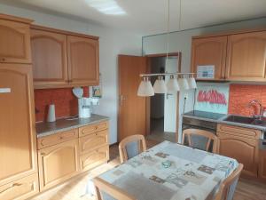 a kitchen with wooden cabinets and a table with chairs at NEU! Nordsee-Ferienwohnung Nicki in Dornum