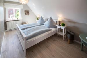 Un dormitorio con una cama con almohadas azules y una ventana en !NEU! Komfort Ferienhaus Polly, en Dornum