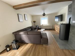 a living room with a brown couch and a television at NEU Ferienhaus Dat Wildberghus in Wildberg