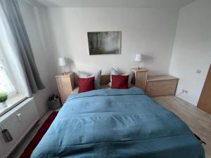 Un dormitorio con una gran cama azul con almohadas rojas en FeWo Milchstrasse Halle, en Halle an der Saale