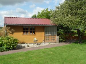 a small yellow house with a red roof at Ferienwohnung Aurich Ostfriesland in Aurich