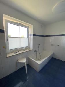 un bagno con vasca, sedia e finestra di NEU Ferienhaus Dat Wildberghus a Wildberg