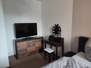 a bedroom with a television and a dresser with a chair at FeWo Franja Angermünde in Angermünde