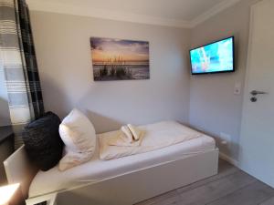 a room with a bed with a television on a wall at NEU! Ferienhaus Musenburg Apartment W1 in Stedesand