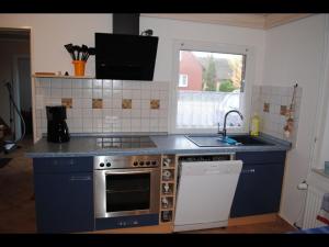 a kitchen with a sink and a stove top oven at NEU! Ferienhaus NordseeGlück in Dornum +11 photos