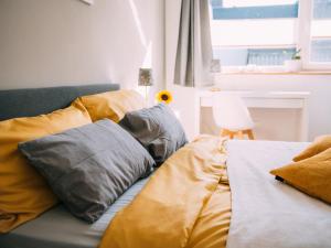 ein Bett mit gelben und grauen Kissen darauf in der Unterkunft NEU! Ferienhaus Handeloh in Handeloh