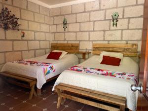 two beds in a room with a brick wall at Boutique la Posada de Don Luis in Bernal