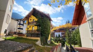 a yellow house with ivy on the side of it at VILA GALBENA - Poiana Brasov in Poiana Brasov