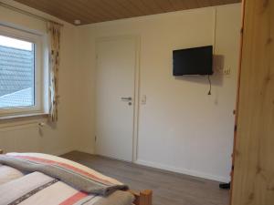 a bedroom with a bed and a television on the wall at NEU Ferienwohnung Wellenrauschen in Westerholt