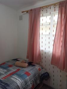 1 dormitorio con 1 cama y una ventana con cortinas rosas en Casa PUQ en Punta Arenas