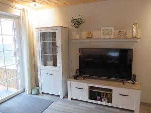 a living room with a tv and a white entertainment center at NEU Huus Inge und Manni in Dornum