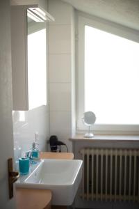uma casa de banho com um lavatório branco e um espelho. em NEU! Ferienwohnungen Glücksmoment Bodensee em Stahringen