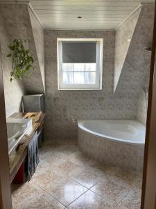 ein Bad mit einer Badewanne, einem Waschbecken und einem Fenster in der Unterkunft NEU Ferienwohnung Hofmann in Husum