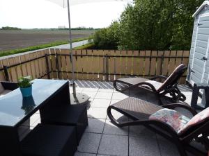 eine Terrasse mit Stühlen, Tischen und einem Sonnenschirm in der Unterkunft !!!NEU!!! Apartment Beagle in Dornumersiel
