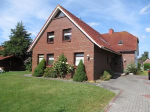 una casa in mattoni rossi con alberi nel cortile di !!!NEU!!! Ferienwohnung an der Harle OG a Carolinensiel