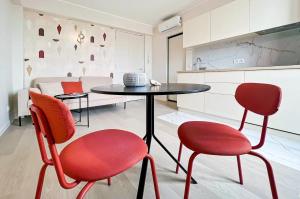 LE PANORAMIQUE في نيس: مطبخ مع طاولة وكرسيين حمر
