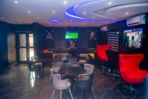 a restaurant with tables and chairs and a television at Triple Tee Hotel & Service Apartments in Ikeja