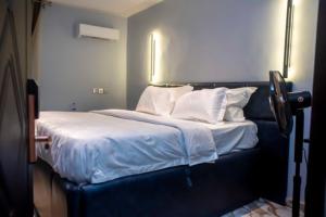 a bedroom with a bed with white sheets and pillows at Triple Tee Hotel & Service Apartments in Ikeja