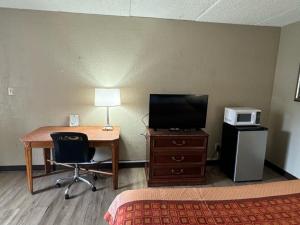 Cette chambre dispose d'un bureau, d'une télévision et d'un lit. dans l'établissement Heritage Inn, à Milledgeville