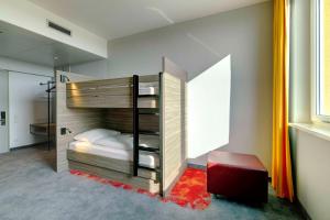 a bedroom with a bunk bed with a red stool at Campanile Berlin Brandenburg Airport in Schönefeld