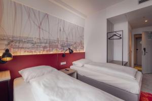 two beds in a room with a painting on the wall at Campanile Berlin Brandenburg Airport in Schönefeld