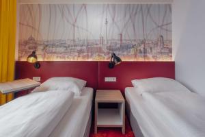 a bedroom with two beds and a window with a painting at Campanile Berlin Brandenburg Airport in Schönefeld
