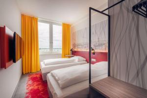 a hotel room with two beds and a mirror at Campanile Berlin Brandenburg Airport in Schönefeld