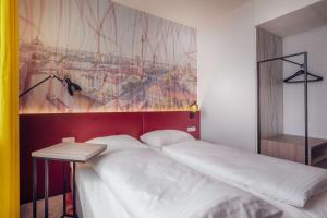 a bed in a room with a painting on the wall at Campanile Berlin Brandenburg Airport in Schönefeld