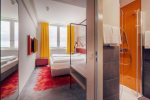 a bathroom with a bedroom with two beds and a shower at Campanile Berlin Brandenburg Airport in Schönefeld