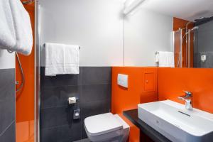 an orange bathroom with a toilet and a sink at Campanile Berlin Brandenburg Airport in Schönefeld