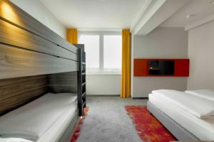a bedroom with two bunk beds and a tv at Campanile Berlin Brandenburg Airport in Schönefeld
