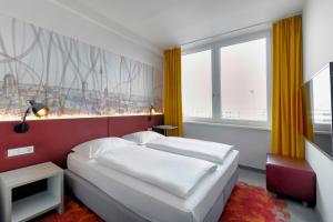 a bedroom with two beds and a large window at Campanile Berlin Brandenburg Airport in Schönefeld