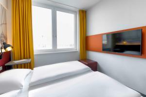 a bedroom with two beds and a large window at Campanile Berlin Brandenburg Airport in Schönefeld