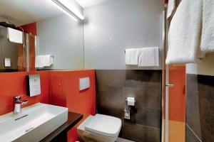 a bathroom with a white toilet and a sink at Campanile Berlin Brandenburg Airport in Schönefeld