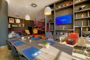 a conference room with a long table and a tv at Campanile Berlin Brandenburg Airport in Schönefeld
