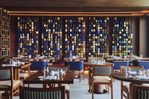 a restaurant with tables and chairs and a wall of wine bottles at Nobu Hotel San Sebastián in Donostia-San Sebastián