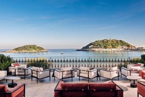 a row of chairs and tables on a patio overlooking the ocean at Nobu Hotel San Sebastián in Donostia-San Sebastián