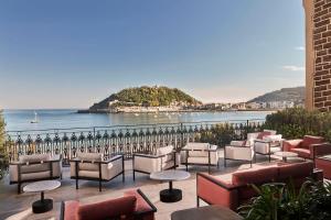 a patio with chairs and tables and a view of the ocean at Nobu Hotel San Sebastián in San Sebastián