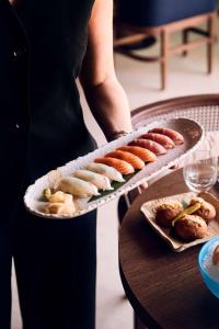 a person holding a tray of food on a table at Nobu Hotel San Sebastián in Donostia-San Sebastián
