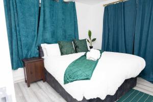 um quarto com uma cama grande e cortinas azuis em 4 bedroom Bungalow em Slades Green