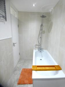 a white bathroom with a tub and a shower at 4 bedroom Bungalow in Slades Green