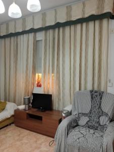 a living room with a chair and a television at Habitaciónes Privadas Cartagena Murcia in Cartagena