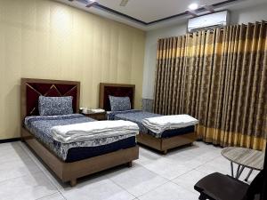2 camas individuales en una habitación con cortinas en The Crown en Islamabad