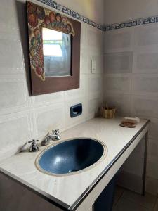 y baño con lavabo azul y espejo. en Granja Relax en Itauguá