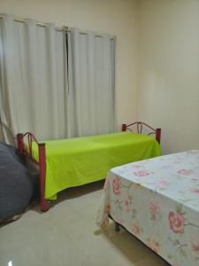 Duas camas com lençóis verdes num quarto com uma janela em Casa Azul em Passos
