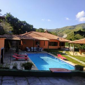 a villa with a swimming pool and a house at Sitio maravilharara in Miguel Pereira